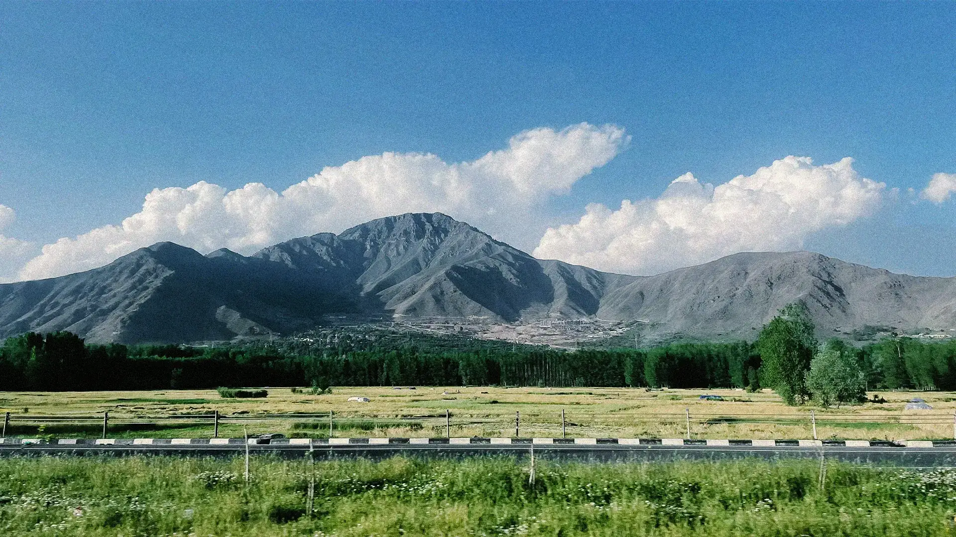 Mountains and open fields under summer clouds